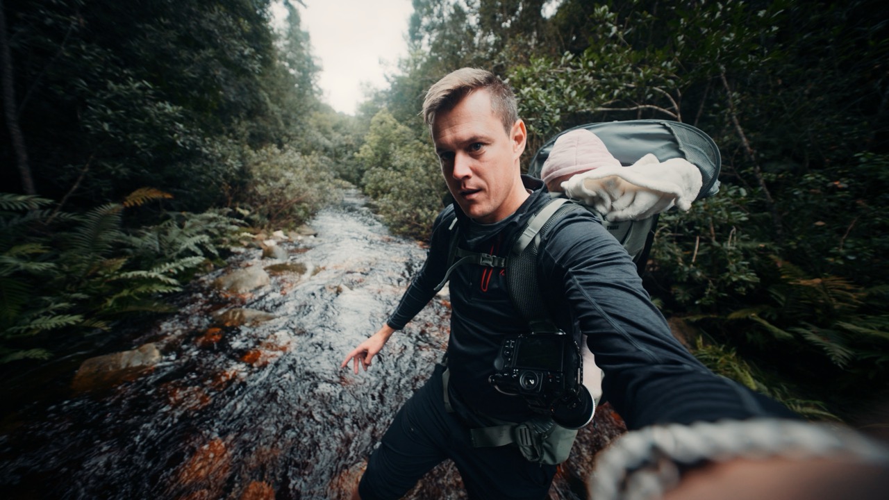 Duan carrying his child during a family adventure beside a river