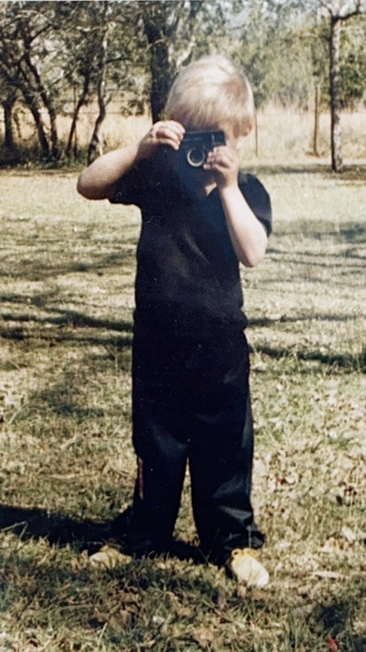 Young Duan holding a camera outdoors